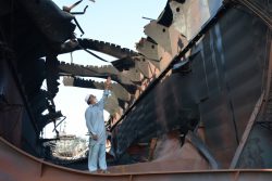 燃え尽きた石油タンカーの中に立ち、爆発で引き裂かれた箇所を指差す船舶解撤労働者のナシーブ・グル。 写真：インダストリオール/Amar Guriro 