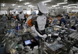 日本の工場の組立ラインで従業員と並んで働く人型ロボット 写真提供：ロイター/Issei Kato 